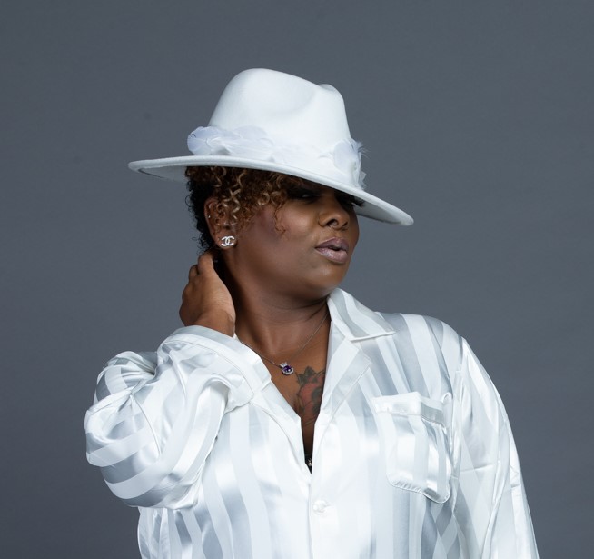 A woman in white shirt and hat holding her hand up to the side of her head.